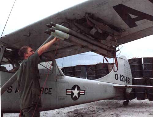 Personel sedang mengecek roket FFAR di sayap Bird Dog,.